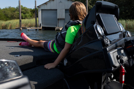 Child relaxing on a boat near a dockside boathouse