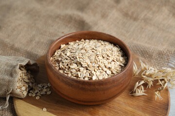 Oat flakes, panicles and burlap on table, closeup