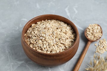 Oat flakes and panicles on light grey table, closeup