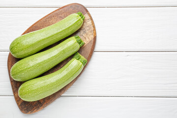 Fresh ripe zucchinis on white wooden table, top view. Space for text