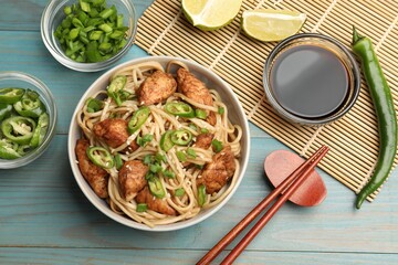 Tasty noodles with chicken, green peppers and sesame seeds served on blue wooden table, flat lay