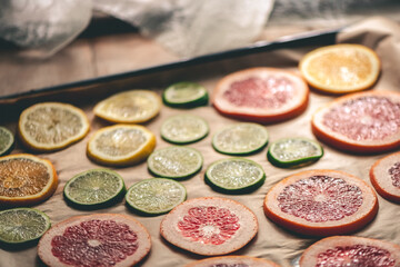 Sliced orange, tangerine and grapefruit slices on baking sheet, preparing citrus wedges for Christmas garland