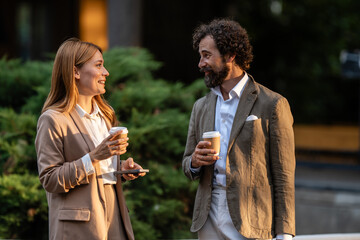 Business people talking and drinking coffee during break outside office building