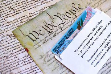 Permanent resident green card in envelope lies on US constitution page