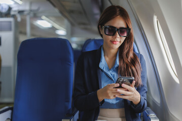Businesswoman using smartphone on airplane during flight