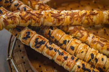 Twisted puff pastry rolls with golden flaky crust, topped with cheese and chocolate sprinkles in bamboo tray perfect for showcasing baked texture, sweet and savory snack appeal.