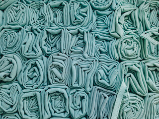 A stack of colorful hijabs or headscarves neatly folded into a square roll. A head covering for Muslim women.