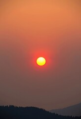Fototapeta premium Orange sky, vibrant sun, hazy atmosphere; climate change, global warming, environmental damage, ecological crisis, impact, warning
