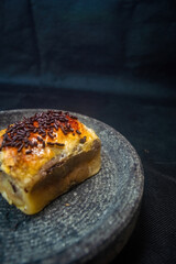 Golden puff pastry slice with glossy crust and rich filling, topped with chocolate sprinkles on dark plate perfect for showcasing baked texture, sweet topping, and dessert appeal.