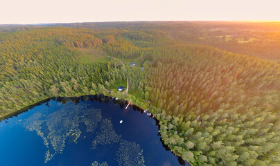 Aerial view, Forest lake at sunset with huts and golden landscape