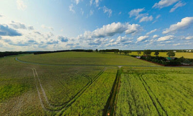 Wide landscape, fields, forests and clouds under a sunny sky in a rural setting.