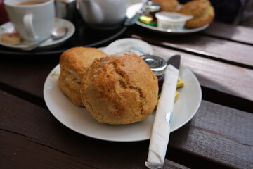 Close up of cream tea scones on a plate with cup of tea.