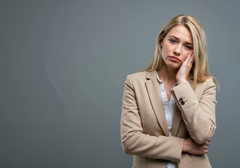 Businesswoman looking stressed while standing against grey background