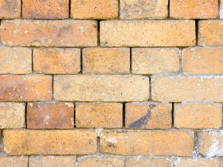 Yellow and orange brick wall with weathered surface close up