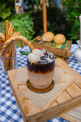 Charming Beverage Delight: An artfully presented coffee drink in a glass. Next to the drink sits small food item. All this rests upon a charming table, ideal for cafe promotions.