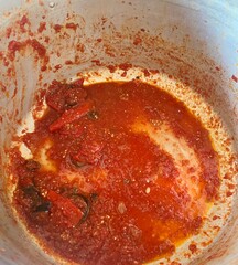 Tomato sauce with eggplant and red bell pepper in the pot. Red sauce with dried tomatoes, capsicum, aubergine and garlic in the aluminum sauce pan. Tomato paste