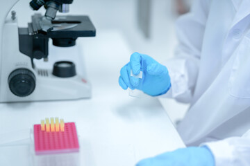 A medical researcher in a laboratory uses a pipette to transfer a liquid sample from a tray of tips. This is a key step in preparing for DNA analysis or other scientific tests.