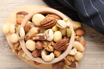 Mix of different nuts in bowl on wooden table, top view