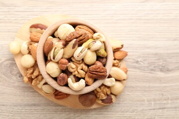 Mix of different nuts in bowl on wooden table, top view