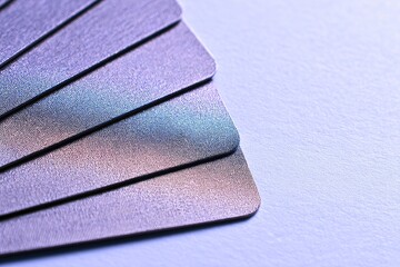 Close-up of several stacked credit cards, angled, showing textured surfaces and iridescent hues