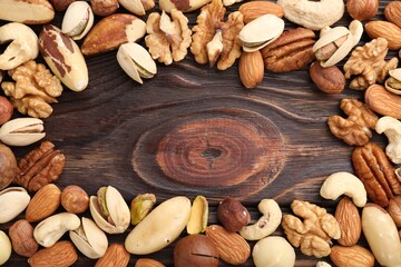 Mix of different nuts on wooden table, flat lay. Space for text