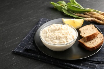 Tasty horseradish sauce served on black table, closeup. Space for text
