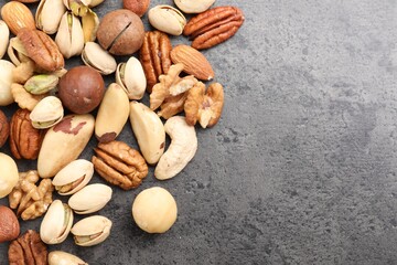 Mix of different nuts on grey table, flat lay. Space for text