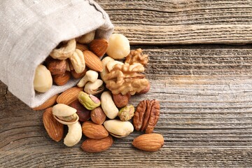 Mix of different nuts in bag on wooden table, closeup. Space for text