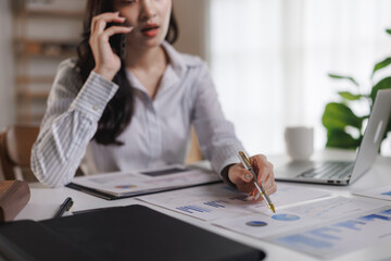 Businesswoman analyzing financial charts and talking on phone