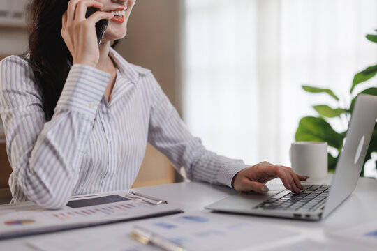 Businesswoman working on laptop and talking on phone