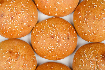 A close-up, top-down shot capturing the fresh, golden-brown homemade sesame seed buns