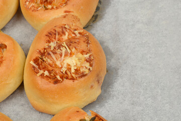 An overhead shot shows several golden-brown baked rolls topped with melted cheese and herbs, arranged on a baking sheet