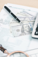 Concept of tax season and financial accounting. Stack of US dollar bills clipped on income tax...