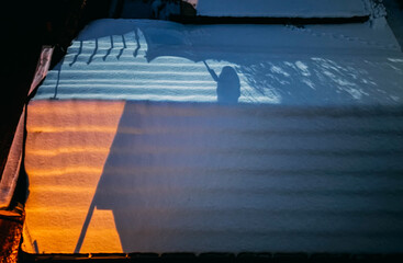 Abstract Shadow of a Person with an Umbrella on Snow at Sunset