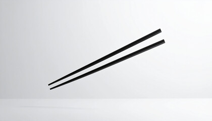 Two black chopsticks isolated against a clean, light gray background, angled.