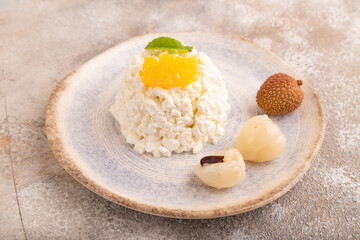 White Сottage cheese, Curd, with orange and lychee on brown concrete, side view, close up.