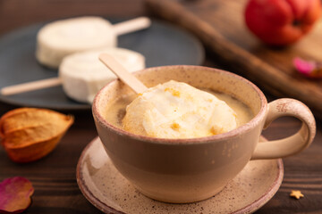 Сhocolate Ice cream in white glaze, cup of coffee, on brown wooden, side view, close up, selective focus