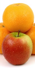 Close-up of oranges and an apple, stacked, wet
