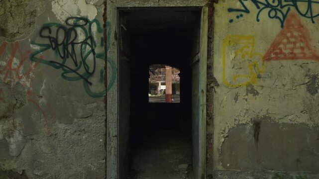Cinematic aerial drone footage gliding through an abandoned factory interior. Slow and atmospheric movement highlights the decayed industrial architecture, broken windows, and empty hallways