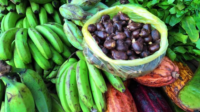 Cacao pods and bananas piled high on a street market, ready for sale