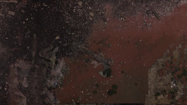 Cinematic aerial drone footage gliding through an abandoned factory interior. Slow and atmospheric movement highlights the decayed industrial architecture, broken windows, and empty hallways