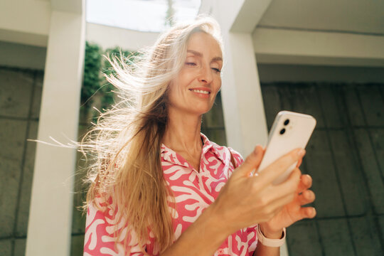 Portrait of a beautiful modern woman using a mobile phone while standing on the street in the city.