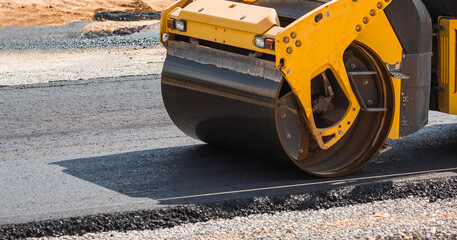 Heavy equipment for earthworks and landscaping. Close-up of a road roller compacting asphalt....