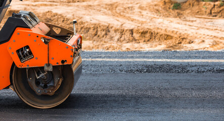 Heavy equipment for earthworks and landscaping. Close-up of a road roller compacting asphalt. Earthworks and road construction.