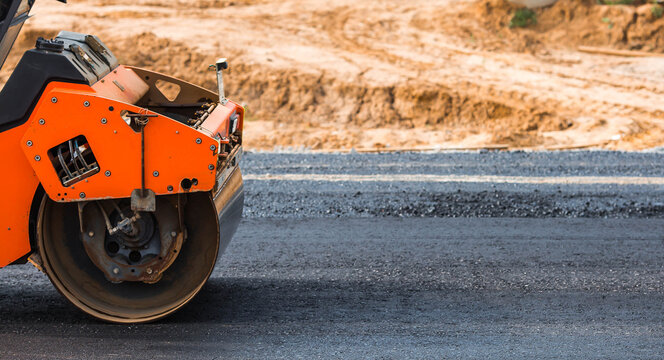 Heavy equipment for earthworks and landscaping. Close-up of a road roller compacting asphalt. Earthworks and road construction.