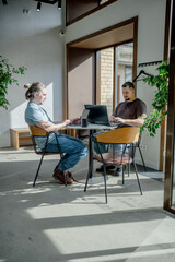 Programmers discussing over laptop working at startup. Office, business and friends together in...