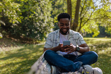 Fototapeta premium Man sitting in a hammock looking at the phone in his hands