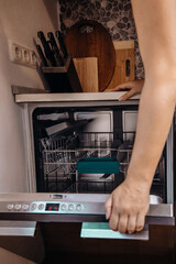 Woman closing dishwasher door after loading