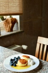 Sweet breakfast. Cheesecakes with blueberries and honey on plate.