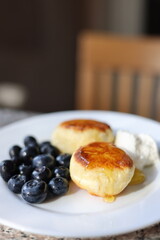 Sweet breakfast. Cheesecakes with blueberries and honey on plate.